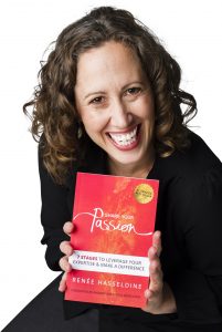 Renee Hasseldine wearing a black blouse on a white background, smiling at the camera and holding a copy of her first book Share Your Passion